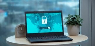 Internet dla biura rachunkowego: specyficzne wymagania bezpieczeństwa danych i pracy na zdalnych systemach Laptop z ikoną kłódki na biurku, symbol bezpiecznego internetu w biurze